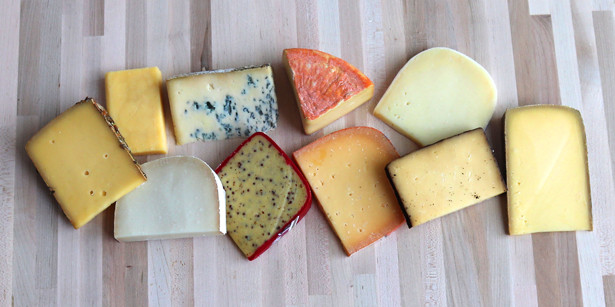 variety of cheeses, cut and displayed on board